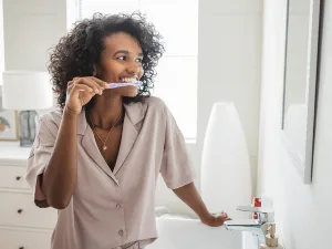 woman brushing teeth in front of mirror