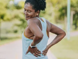 woman outdoors with hands on lower back