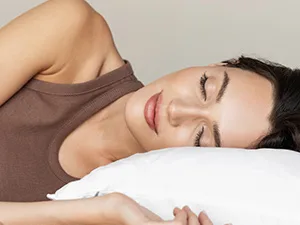 smiling woman laying in bed with head on pillow
