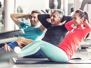 three people doing situps in a gym