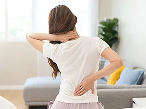 woman sitting on bed with back pain