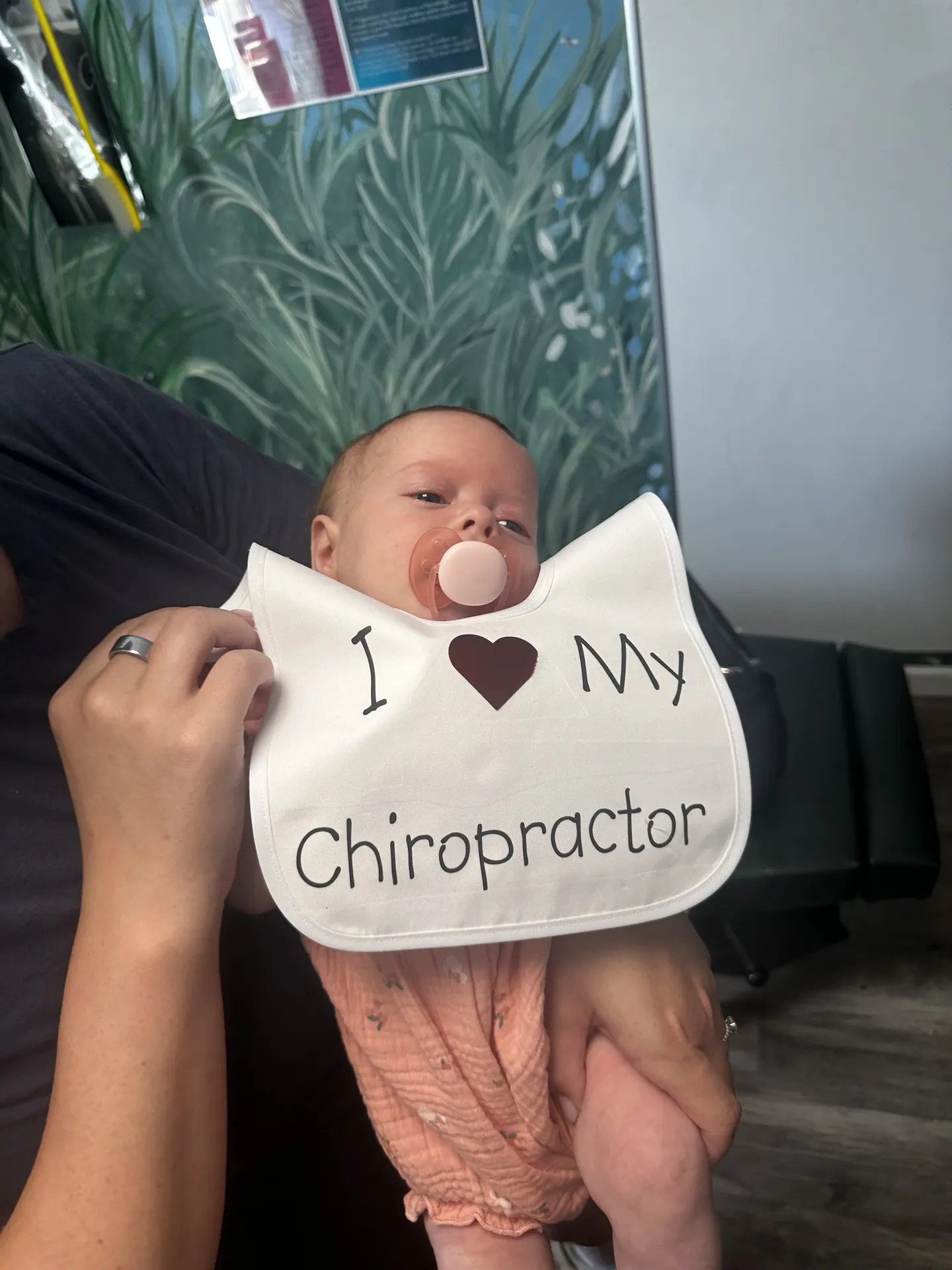 A baby wearing an I love my chiropractor bib