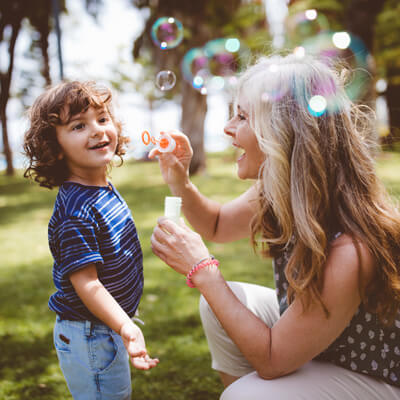Child playing outside chasing bubbles in the park