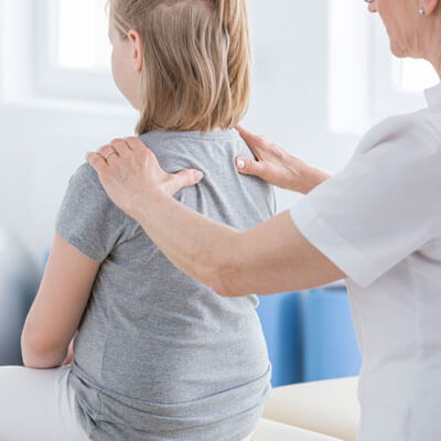 Doctor checking a young girl's spine during an exam