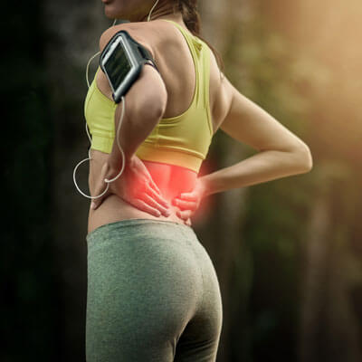 Woman holding her lower back while out for a walk