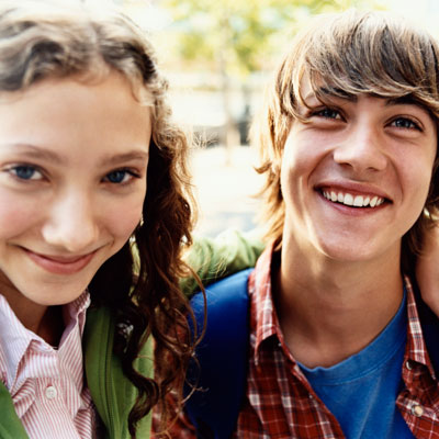 Two smiling teenagers standing outside together