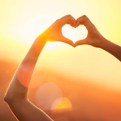 Hands forming a heart shape against the sun