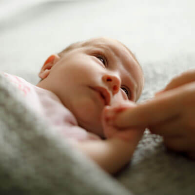Newborn infant holding onto their mother's finger