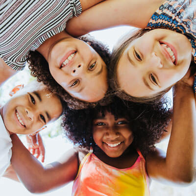 Four smiling children with their heads together in a huddle