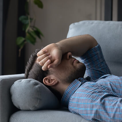 Man resting on the couch, uncomfortable with digestive distress