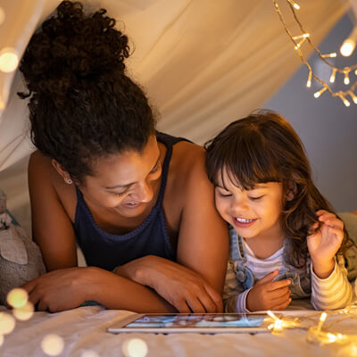 Mother and daughter smiling together in a blanket fort