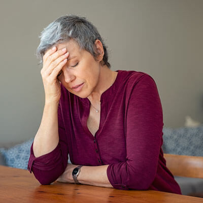 Woman sitting at a table with her hand to her forehead, uncomfortable after a meal