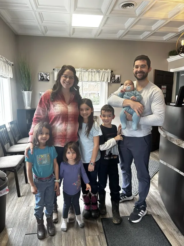 The J. family, parents and five children, at our office