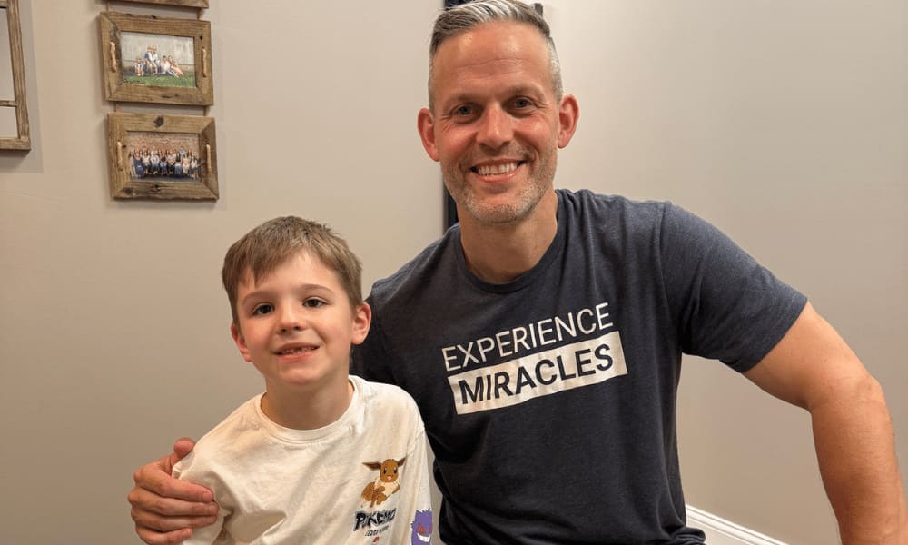 Man in a graphic t-shirt with his arm around a smiling young boy