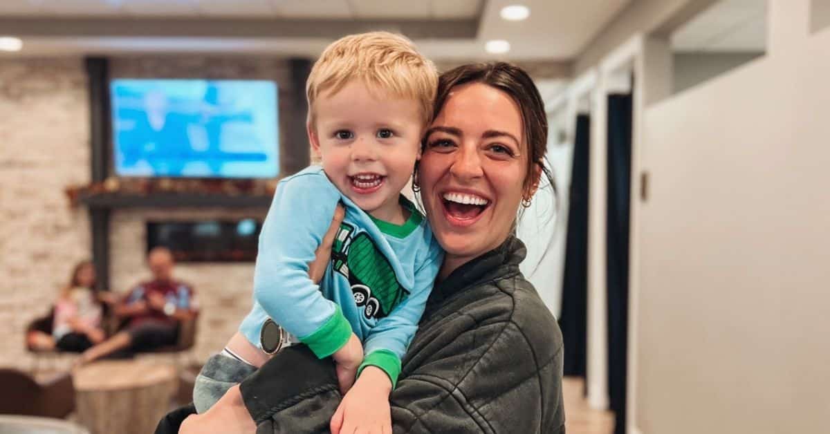 A toddler laughing on his mother's shoulder in the office waiting area