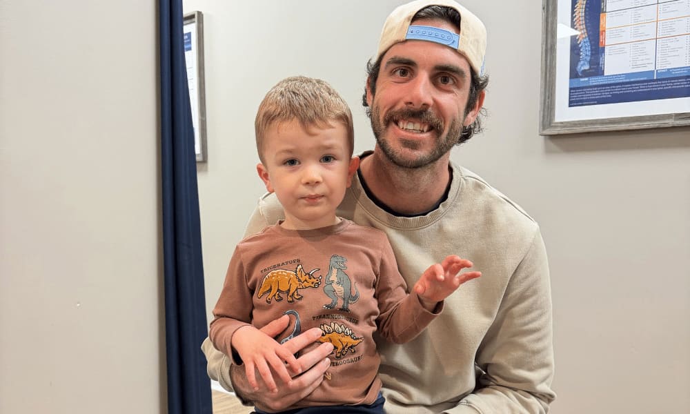 A father holding his young son who is smiling at the camera