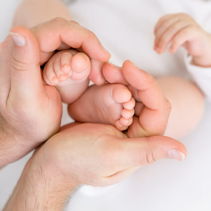 Parent's hands gently cradling a newborn's feet