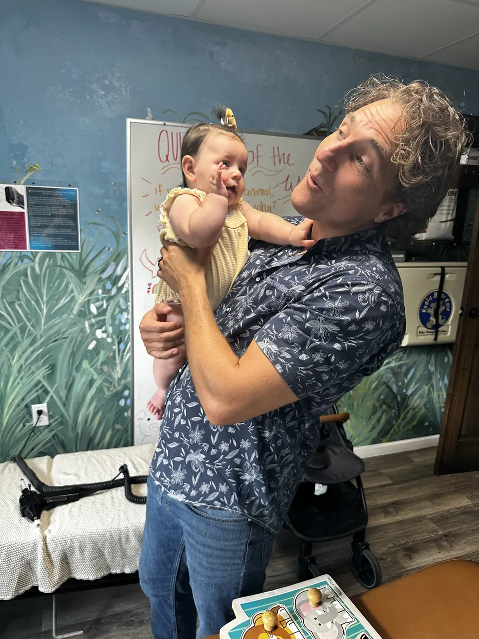 Dr. Zach Conner holding a baby who reaches for his face in our jungle room
