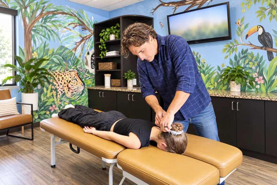 Dr. Zach Conner gently adjusting a child lying face down in our jungle room